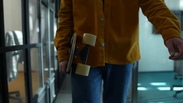 Worker Walking with Skateboard Into Office Space