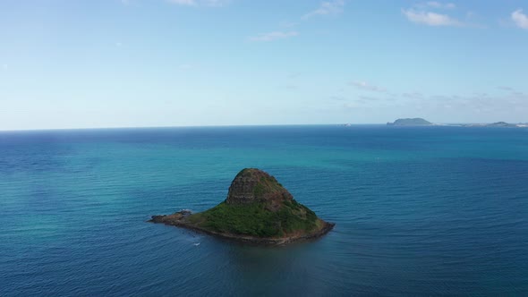 Aerial reverse pullback shot of Mokoli'i island, also known as Chinaman's Hat, on the island of O'ah