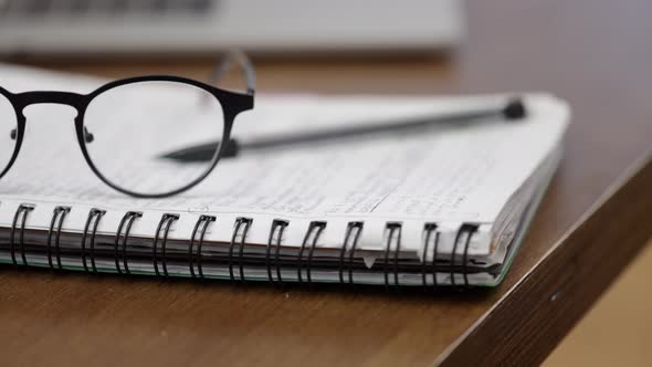 Close up glasses and a pen lie on a pad with springs. Workplace concept.