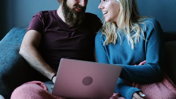 Couple using laptop on sofa at home 