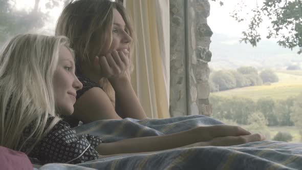 Detail of Two Young Women Friends or Homosexual Lesbian Couple Relax Smile on Bed in the Morning