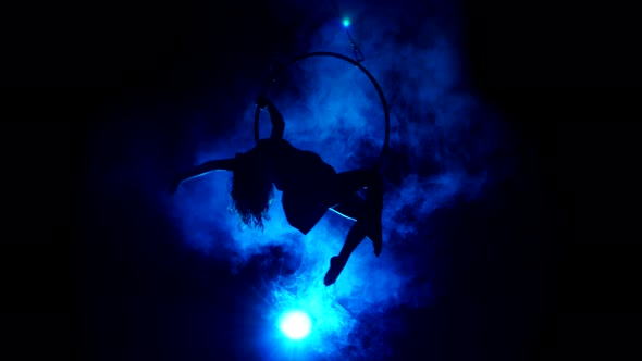 Aerial Acrobat Woman on Circus Stage. Silhouette on a Blue Background.