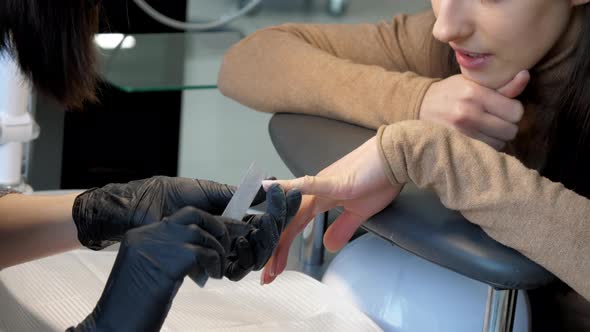 Young Woman Smiles and Looks at Manicurist in Salon