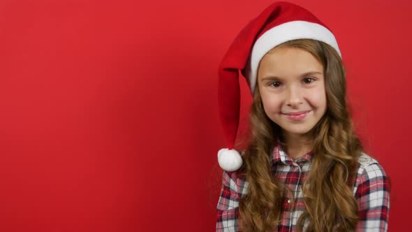 Caucasian Cute Girl With Santa Claus Hat Isolated on Red Background. Christmas Message Concept