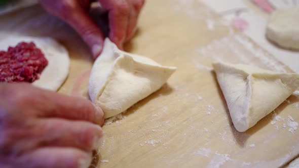 Female Hands Mold Pies Close the Meat Filling in the Dough for Pies