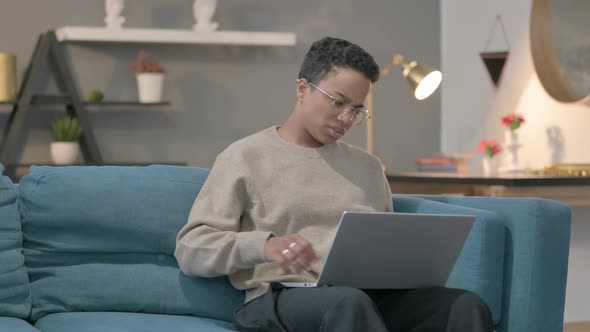 African Woman with Laptop Having Back Pain on Sofa