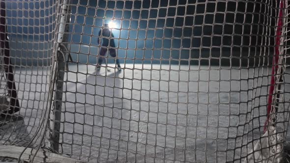 A View Behind the Net of Hockey Forward Who Hits the Puck with His Stick and Scores a Goal