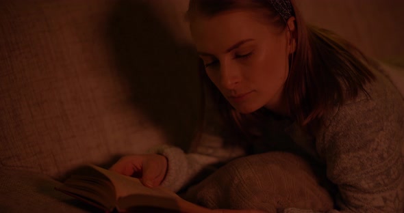 Woman Reading Book Laying on Sofa in Living Room