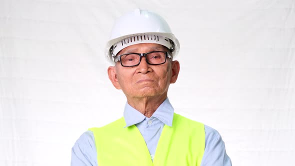 Confident senior engineering architect wearing vest and helmet on white background in studio.