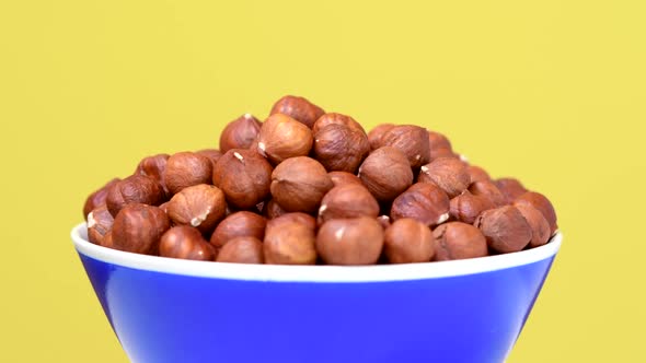 Hazelnuts in Bowl Rotating on Yellow Background
