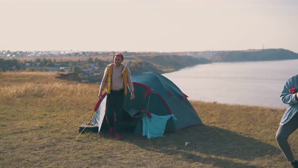 Man Goes Out of Tent and Girls in Camp on Bank in Morning