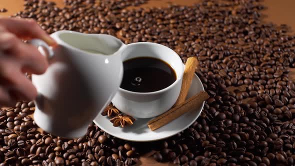 Closeup of Pouring Milk in a Cup of Black Coffee