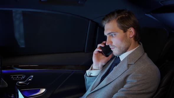 Businessman is Sitting in a Moving Car Talking on a Mobile Phone and Using Laptop Man Top Manager in