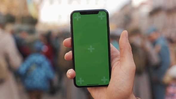 Closeup of a Man's Hand Holding and Using Mobile Telephone with a Vertical Green Screen on the