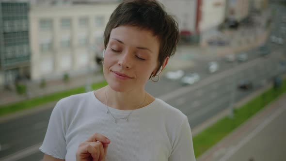 Closeup of the Face of a Brunette Who Gets High From Music Against the Background of the City