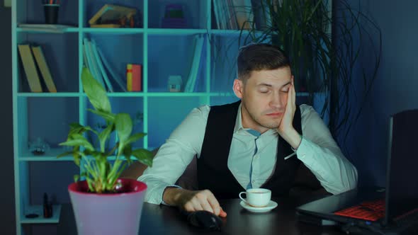 Sleepy Man at Laptop Holding Coffee Cup