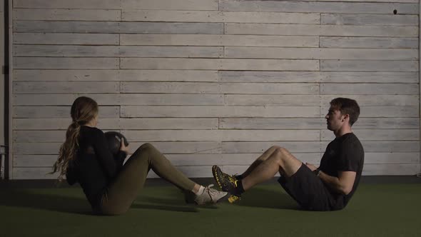 Woman and man tossing medicine ball and doing ab workout