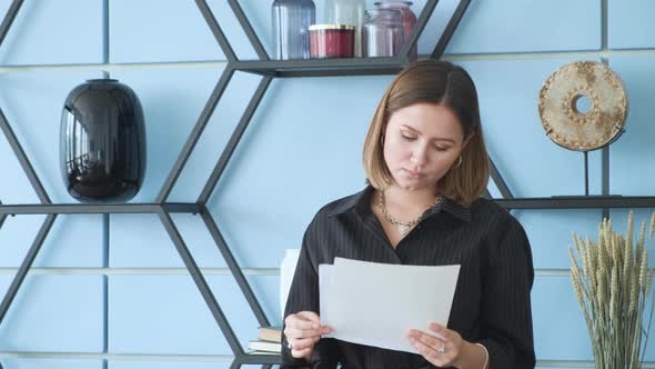 A young business lady stands in the office and looks at the documents