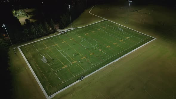 Aerial view of football league at night from above. High angle low light drone shot watching and loo