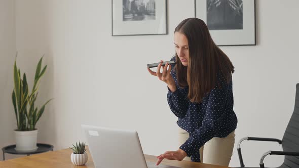 Multitasking Young Businesswoman Using Voice Recognition Function on a Smartphone