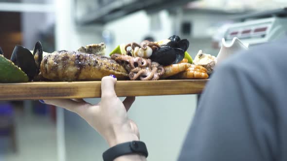 Waitress Carries Wooden Tray with Grilled Sea Delicacies