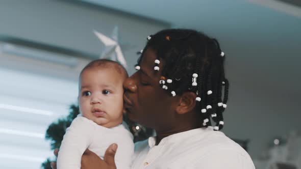 Adorable Multiracial Baby Cuddling with His Father in Front of the Christmas Tree