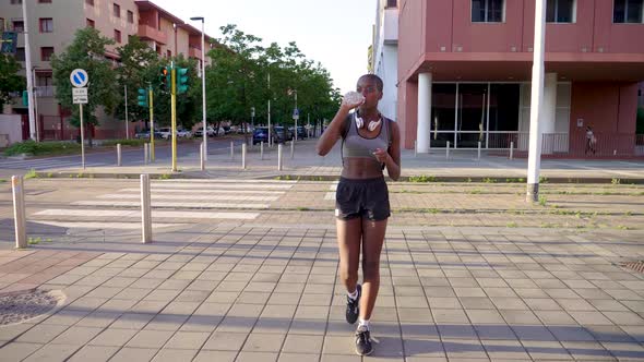 Young woman drinking from water bottle walking in city