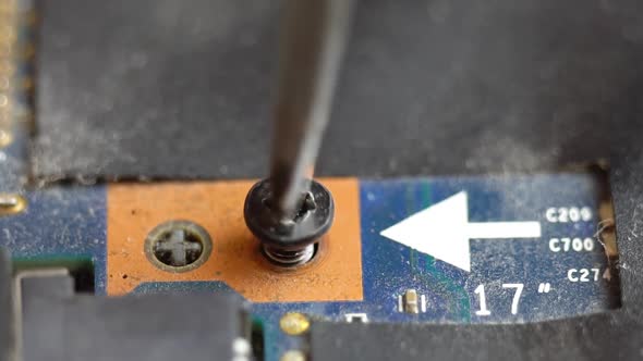 Unscrewing a Screw on a Laptop Motherboard Unscrewing and Tightening a Bolt Into an Integrated Board