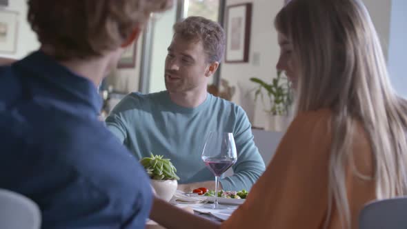 Group of Happy Friends Talking Together Eating Meal Drinking Wine