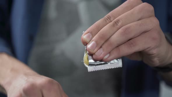 Male Hand Opening Condom Package Before Camera, Contraception, Close-Up