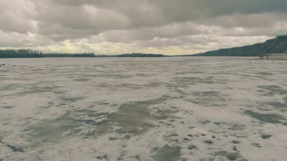 Heavy Grey Clouds Above Dirty Brown Frozen River Surface