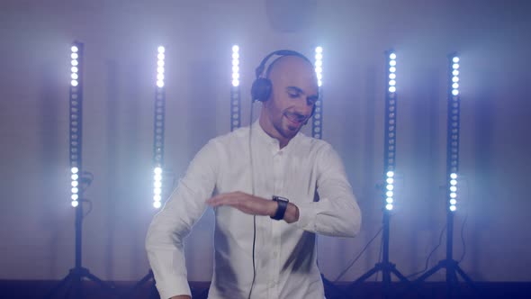 Live DJ Performance of Energetic Bald Man with Headphones Dancing Listening Music From Mobile Phone