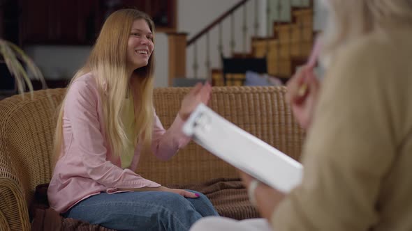 Hysterical Crying Young Woman Sitting on Couch Talking with Blurred Psychologist Gesturing Writing