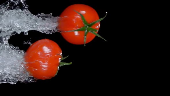 Two Small Cherry Tomatoes are Bouncing Horizontally on the Black Background