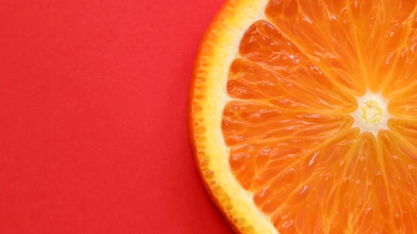 Slice of Orange Rotating Close-Up on Red Background