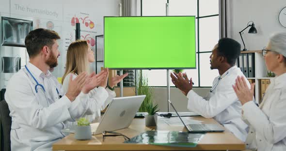 Team of Doctors Sitting in front of Green Chroma Key Screen and Clapping Hands