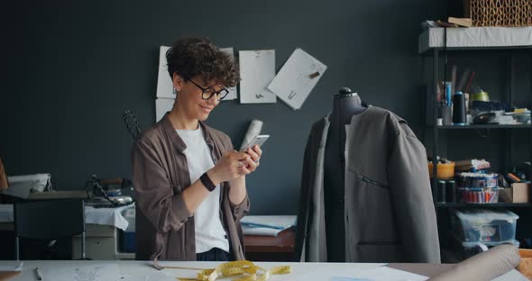 Female Fashion Designer Using Smartphone During Break at Work Smiling