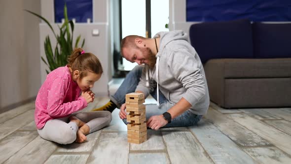 Happy Handsome Father and Happy Daughter Play Game with Wooden Tower Blocks Bricks