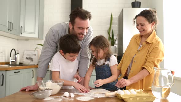 Happy Family of Four Cooking in the Kitchen Together Parents and Two Kids Making Dough Together