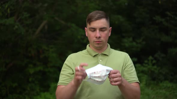 A Young Man Removes the Medical Mask with the Inscription is Enough and Holds It Forward