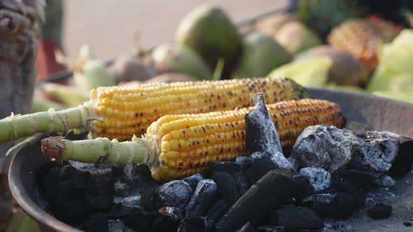 Sweet Corn Cob Roasting on a Coal and Street Vendor Turning It