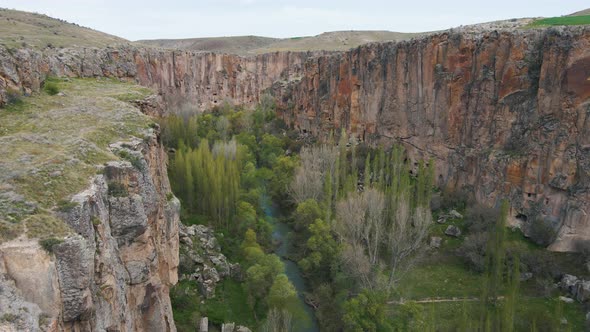 Aerial drone shot over river passing through Ihlara Canyon in Cappadocia, Turkey on a cloudy day.