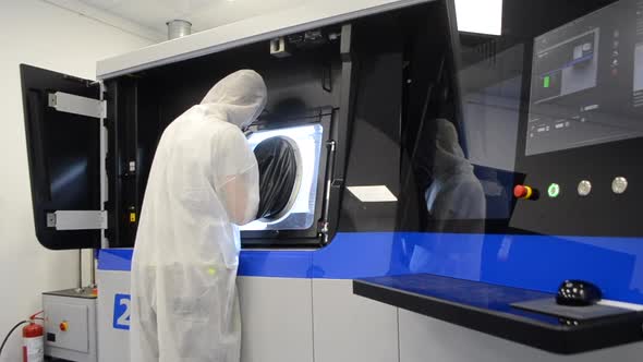 Person in White Overalls Works with Machine with Large Rubber Sleeves