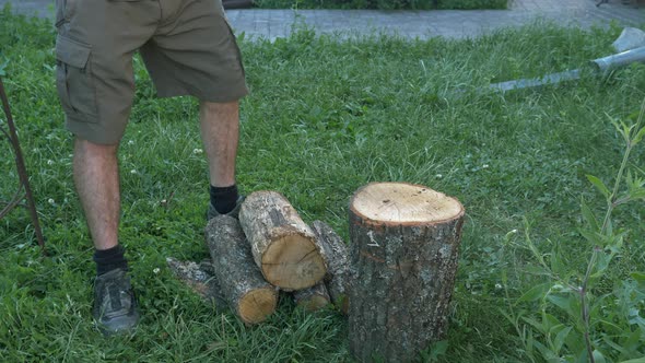 Caucasian male logger chopping wood with axe outside on sunny day.