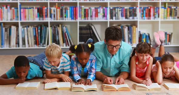 Teacher and kids lying on floor reading book in library