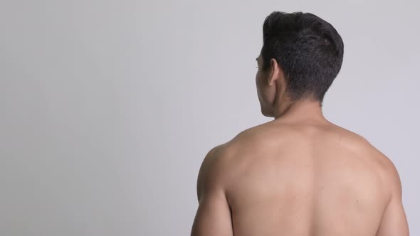 Rear View of Young Handsome Muscular Shirtless Man Looking Back