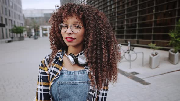 A Beautiful African American Ethnicity Girl with Headphones Around Her Neck Stands in the Middle of