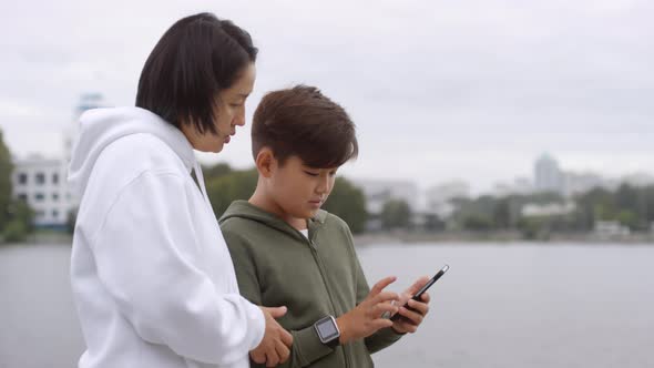 Asian Mother and Son Using Smartphone before Outdoor Workout