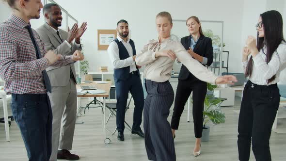Flexible Young Woman Dancing at Corporate Party Moving Among Colleagues Who are Having Fun and