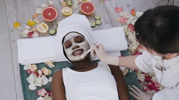 Young African Woman Relaxing while Cosmetologist Makes Procedure of Cleansing